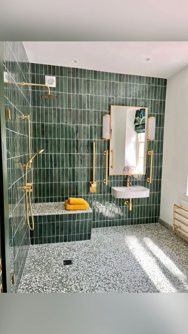 Walk-in shower with green tiles, gold fixtures, and a built-in tiled bench.