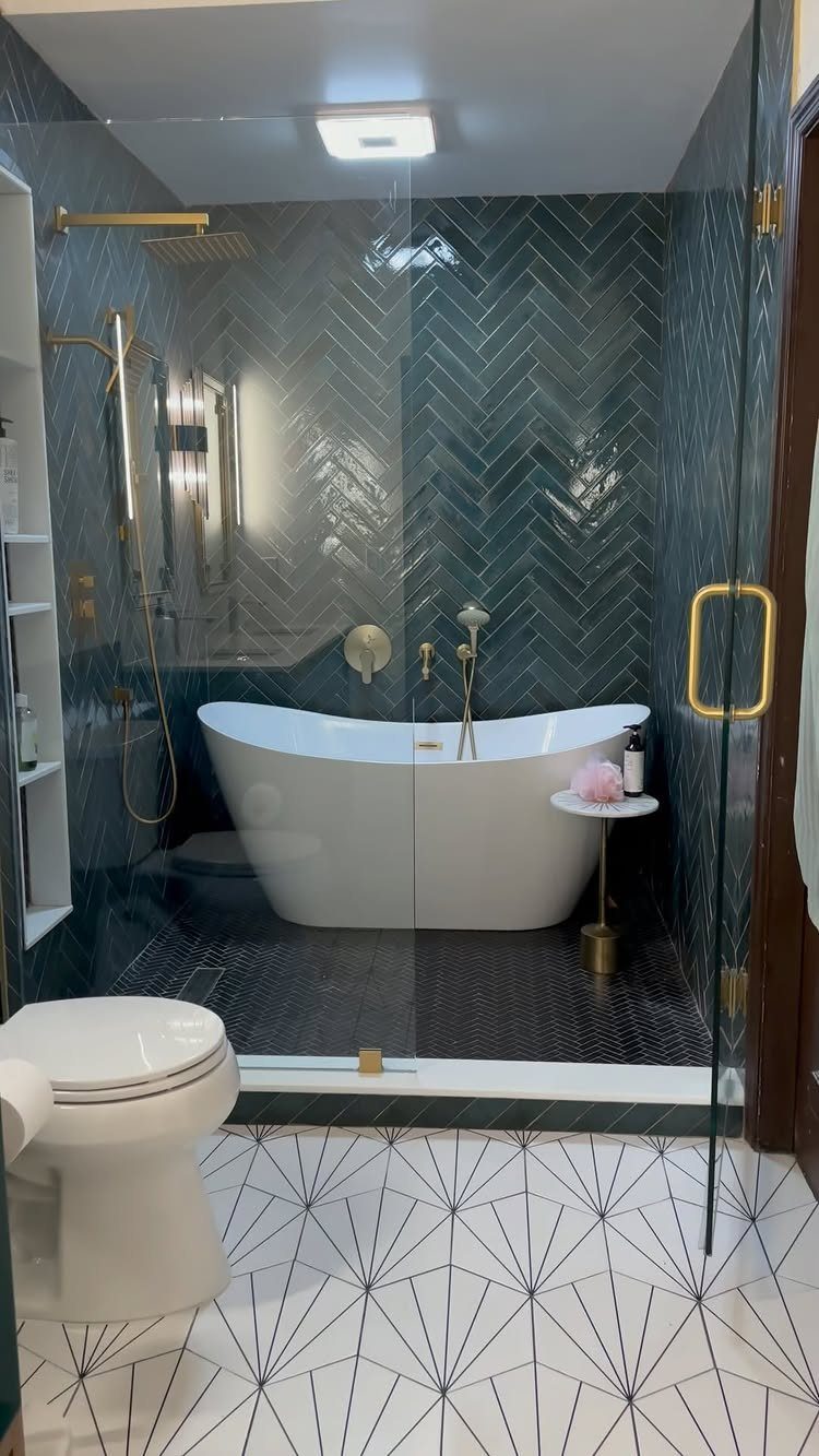 Small bathroom with teal herringbone tiles, white bathtub, and gold shower fixtures.
