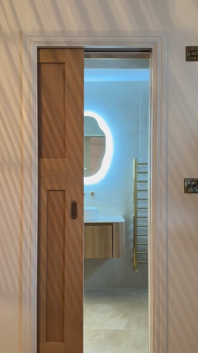Wooden pocket door sliding open into a modern bathroom with floating vanity.