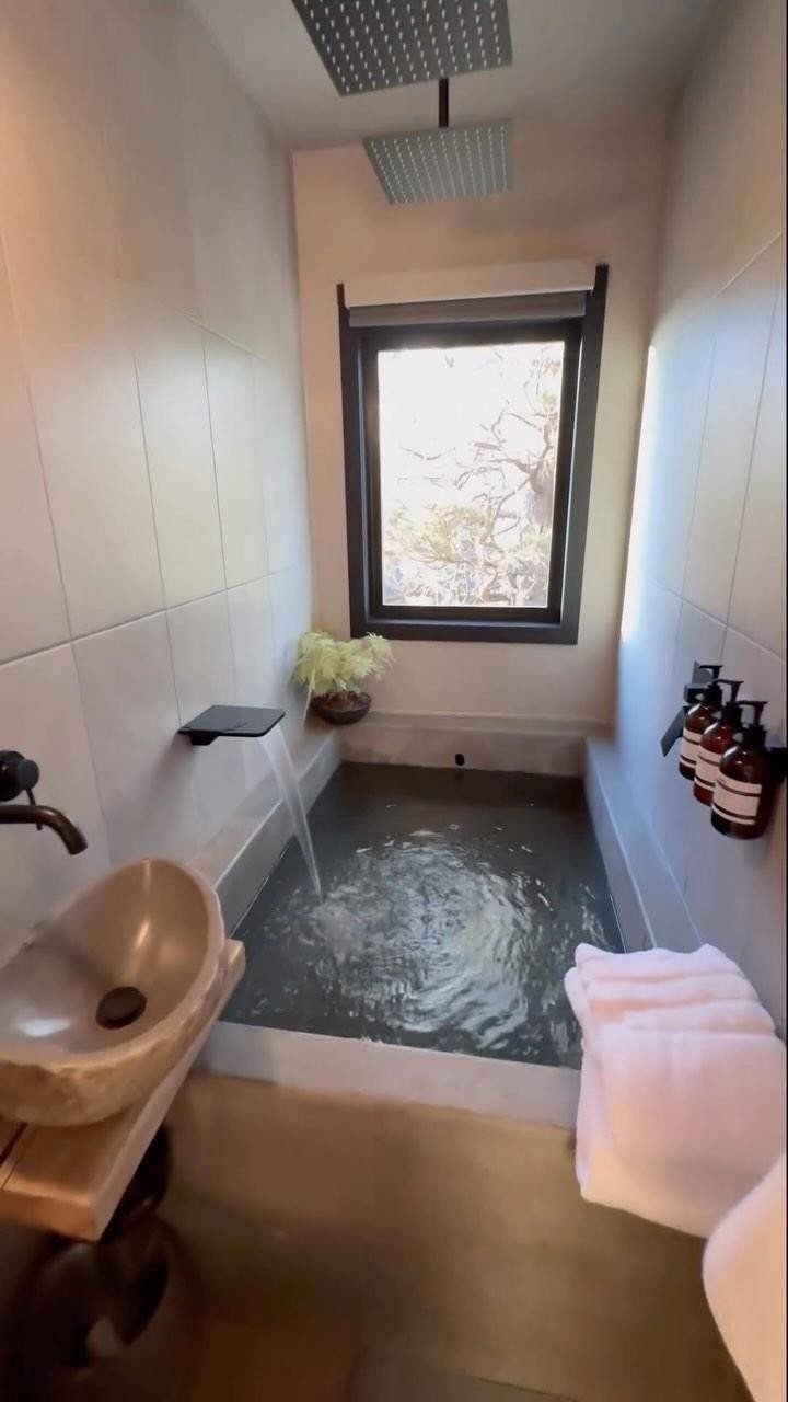 Deep grey stone soaking tub in a narrow bathroom with white tiled walls.