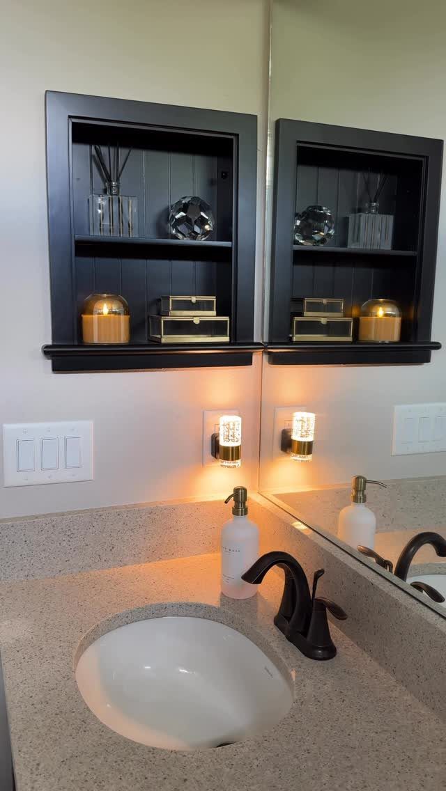 Black-framed recessed wall shelf with decorative items above a bathroom vanity sink.