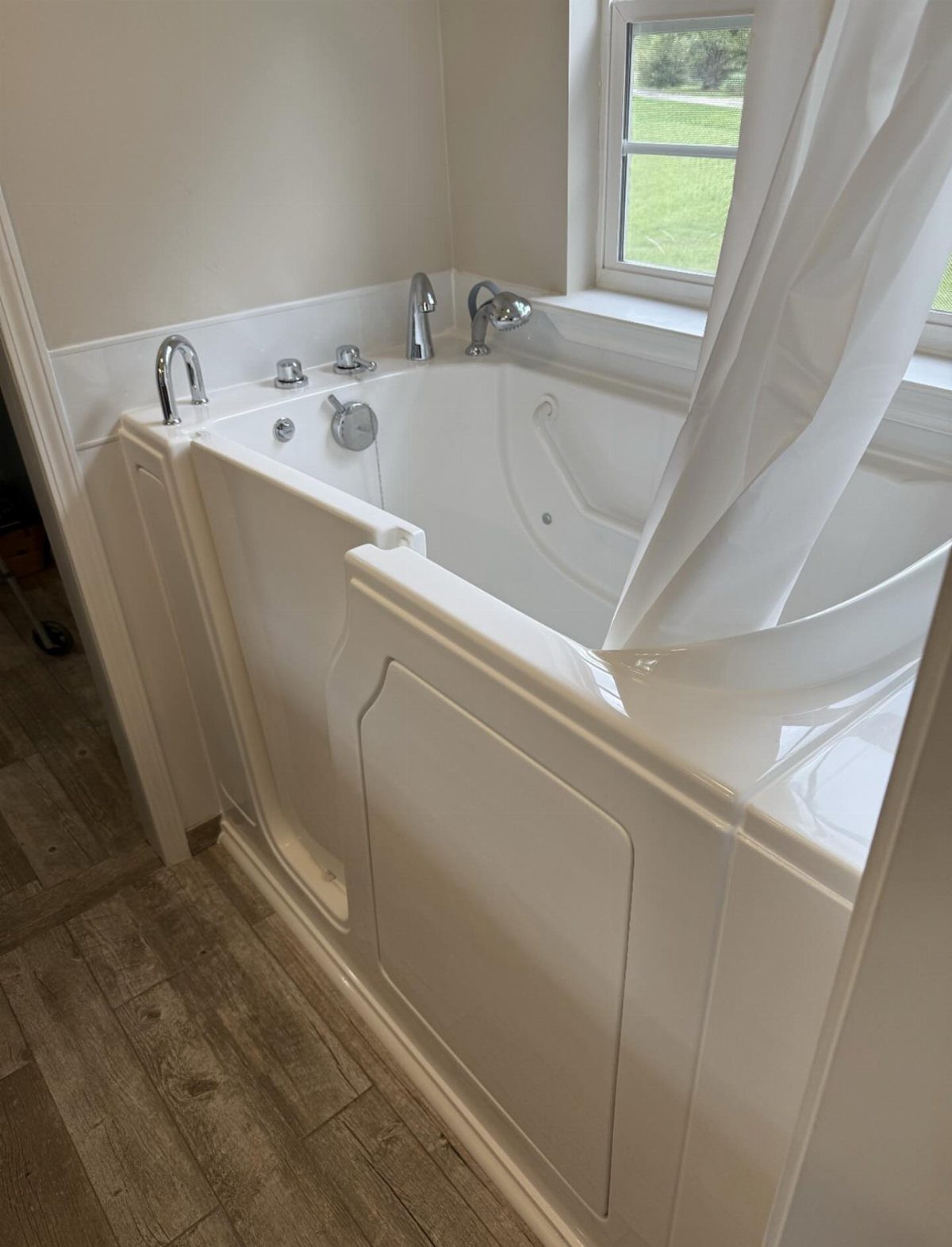 White walk-in bathtub with a side access door in a bright bathroom.