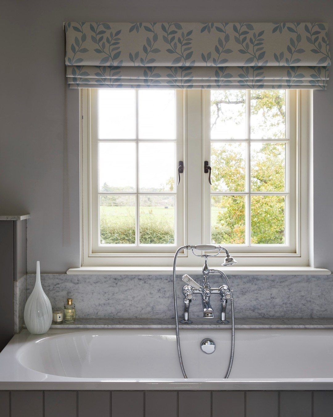 White casement window with grids above a bathtub in a bright bathroom.
