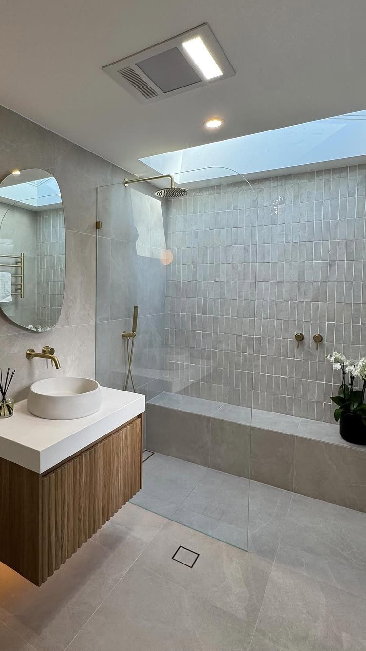 Modern grey bathroom featuring a walk-in shower and a bright ceiling skylight window.