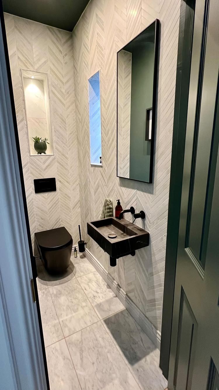 Narrow bathroom with white herringbone tiles and a slim vertical window