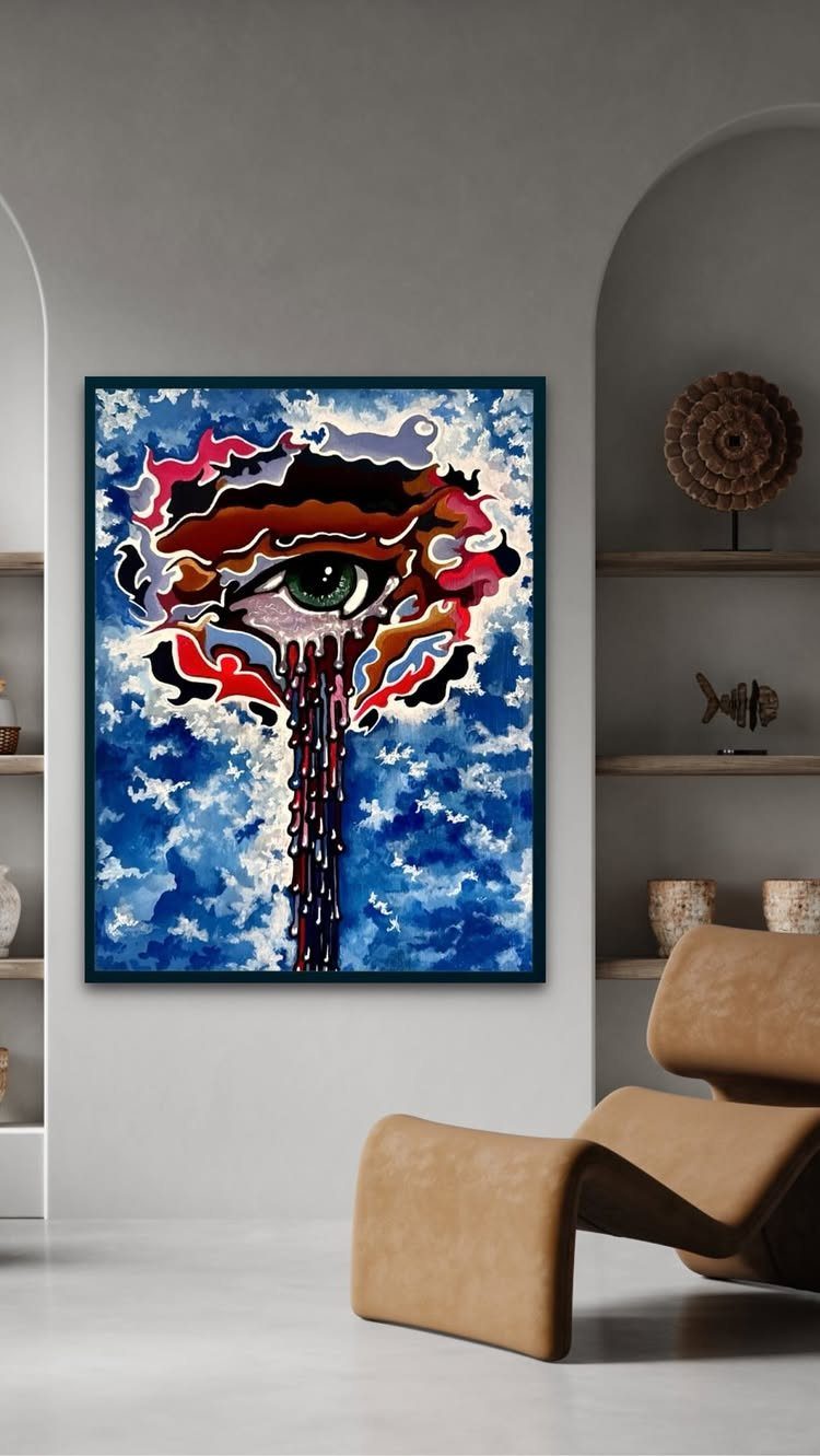 Colorful painting of a crying eye hanging on a grey wall above a tan chair