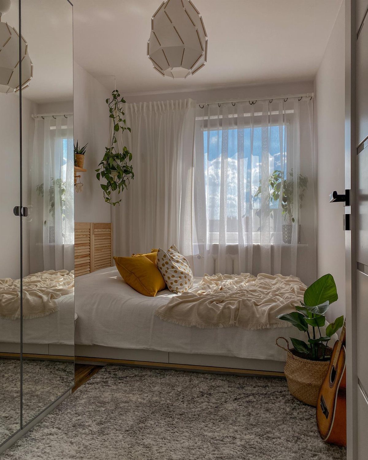 Bright small bedroom with sheer white curtains allowing natural light to fill the space.
