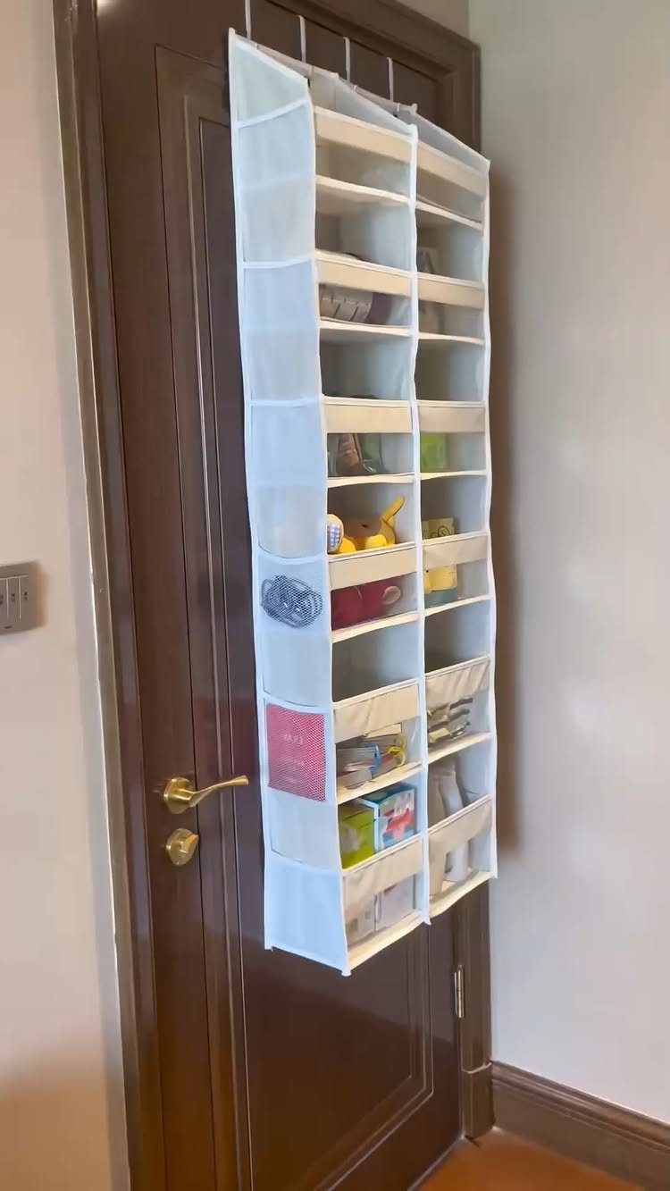 White fabric hanging organizer with pockets attached to a dark brown wooden door.
