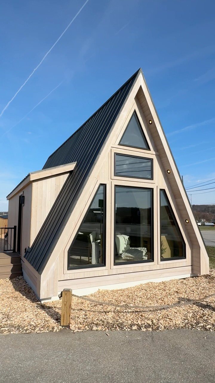 A-frame small house with light wood siding and large front glass windows.