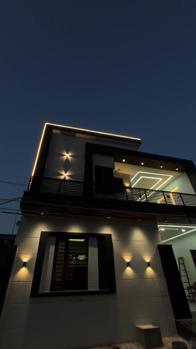 Modern small house exterior at dusk featuring warm yellow architectural outdoor lighting.