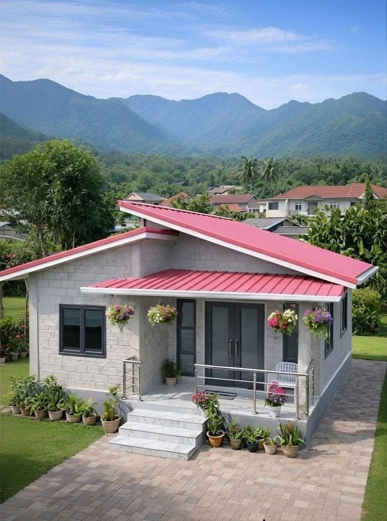 Small grey concrete house with a red roof and porch against mountain backdrop