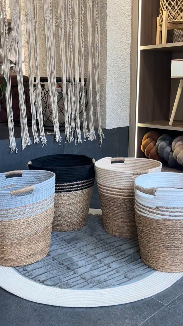 Four woven rope baskets in neutral colors resting on a grey textured rug.