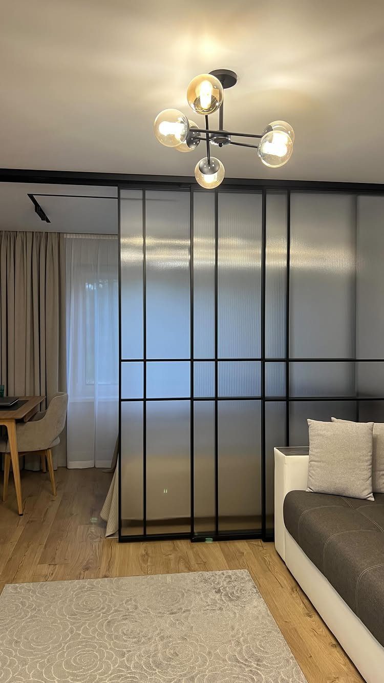 Black-framed frosted sliding glass doors separating a living area from a dining space.