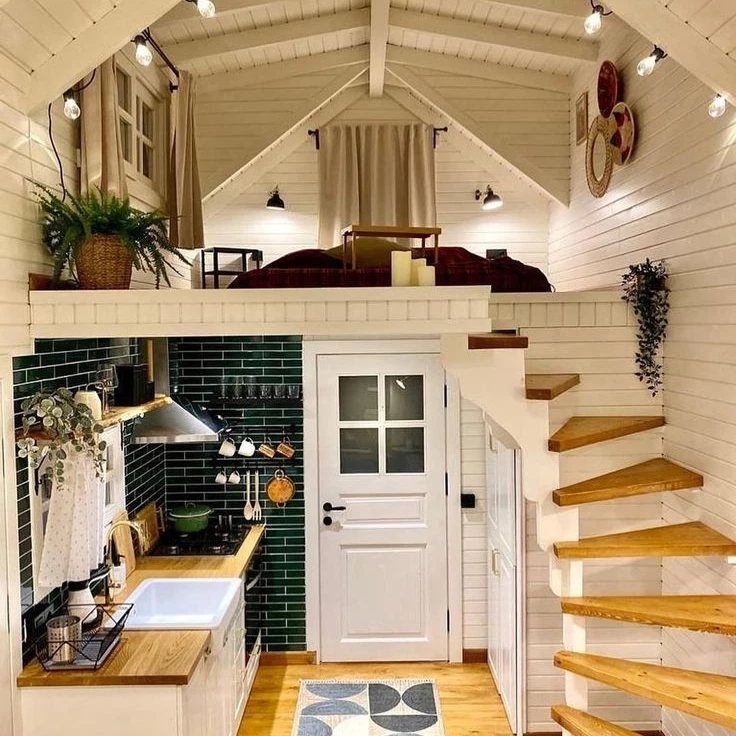 Tiny house interior with a green tiled kitchen and a loft bedroom upstairs.