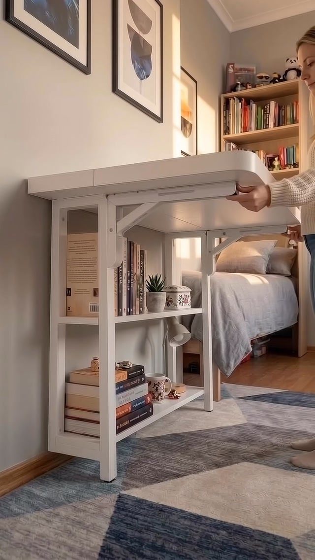 White fold-down desk being opened in a small bedroom with a bed and rug.