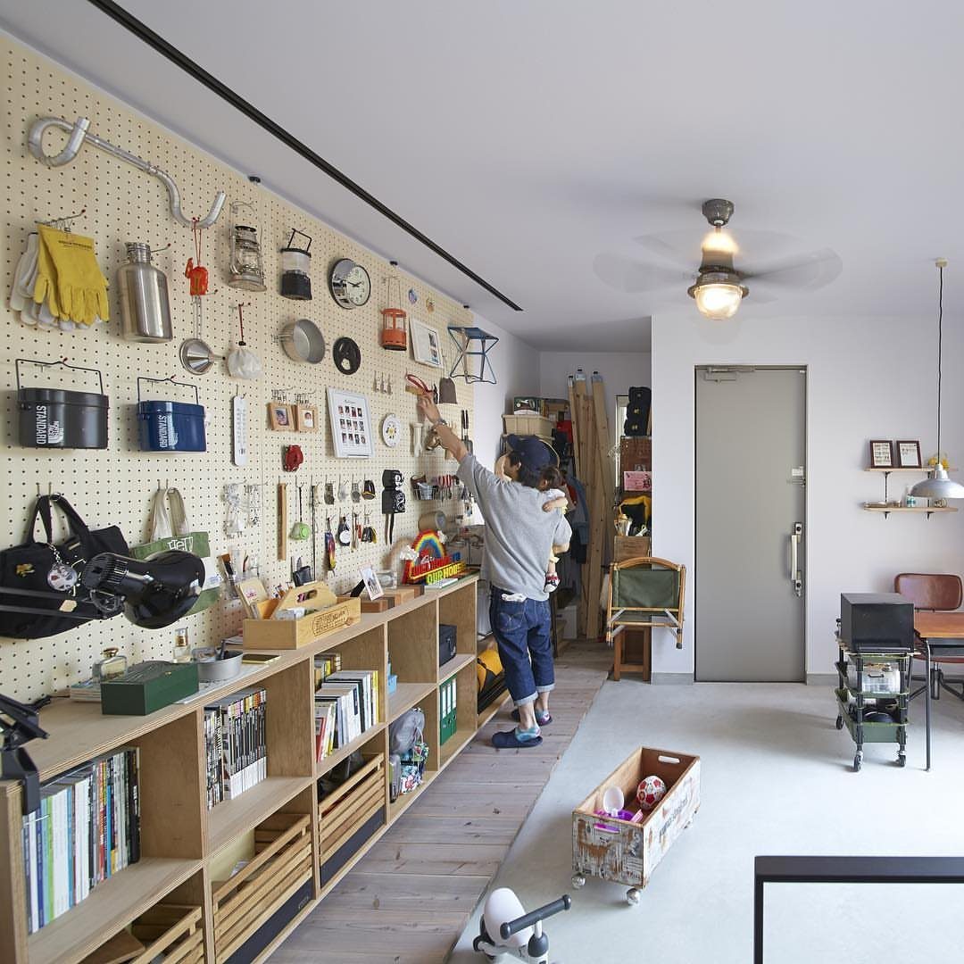 Person organizing tools and items on a large wall-mounted pegboard storage system.