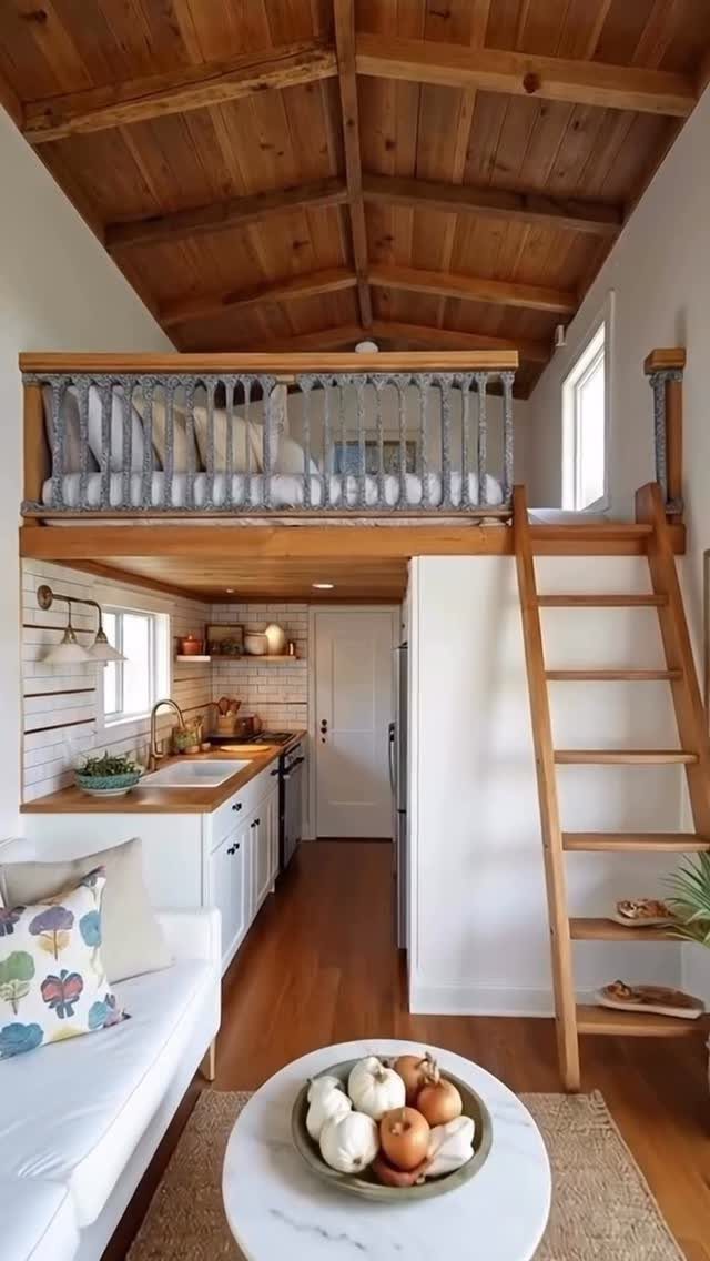 Wooden vaulted ceiling above a lofted bedroom and compact kitchen in a small home.