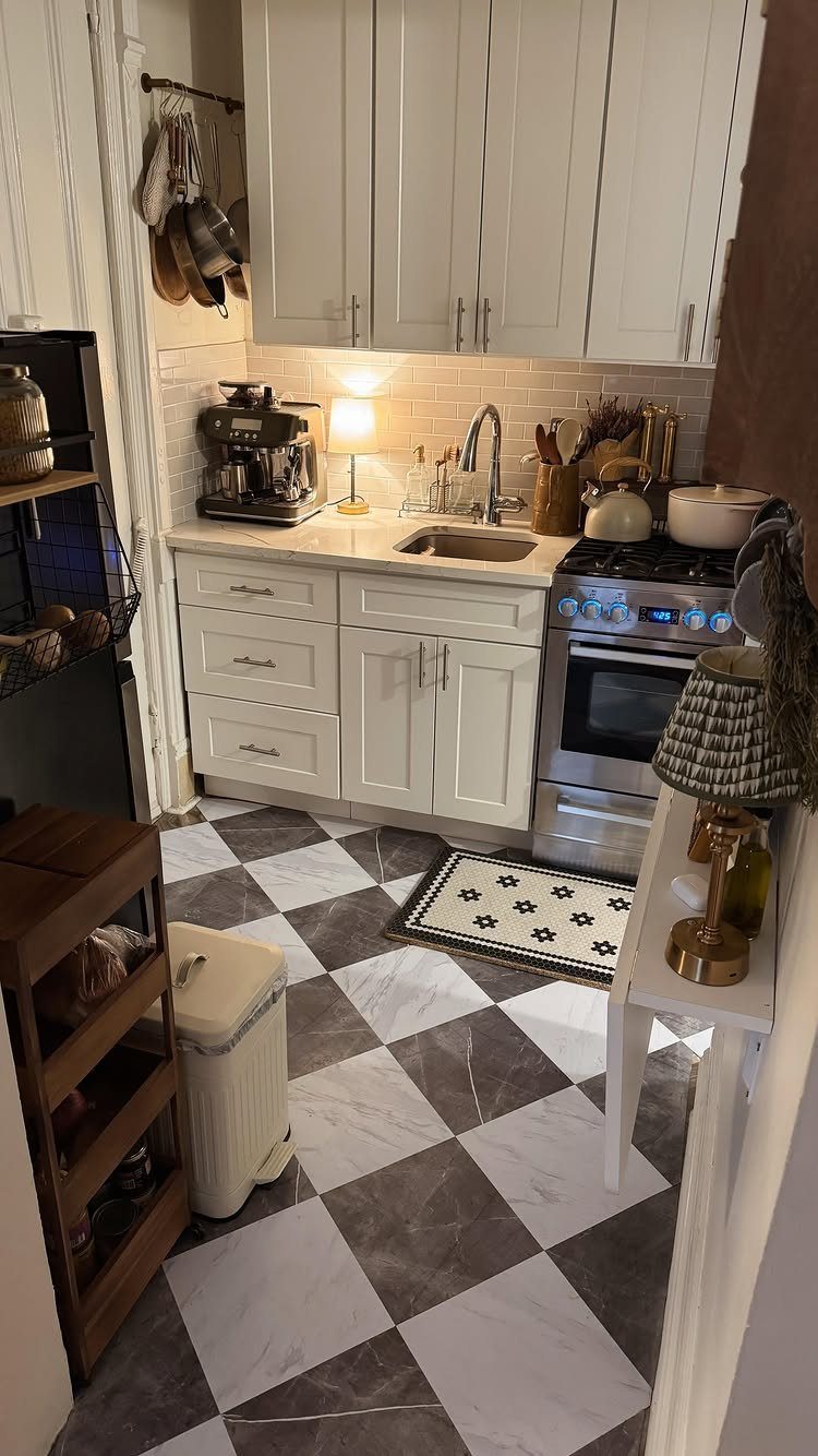 Small kitchen with white cabinetry, checkered flooring, and compact stainless steel appliances.