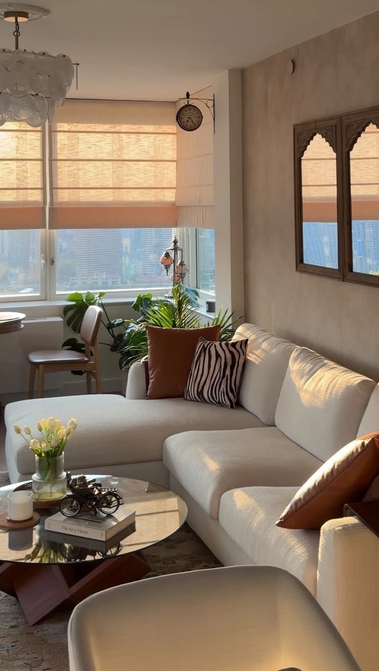 White sectional sofa in a bright room with arched mirrors reflecting a window view.