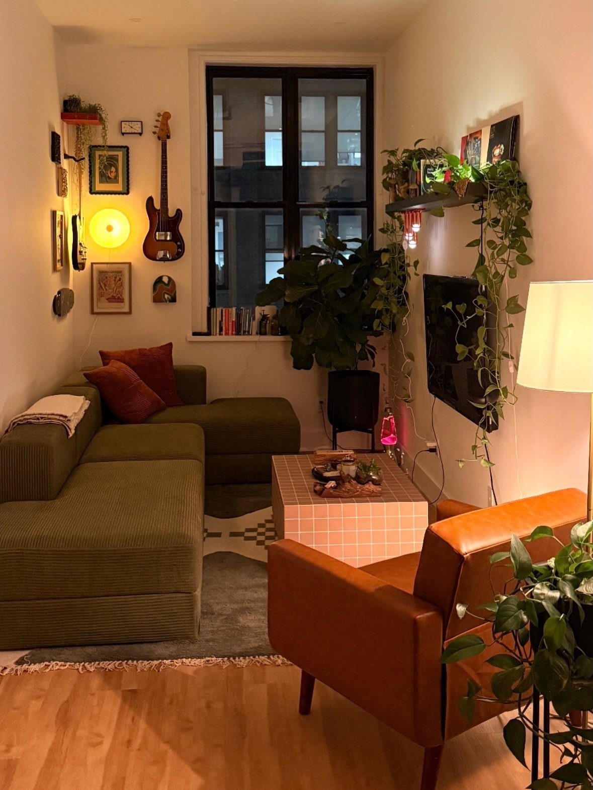 Small living room with white walls, light wood floors, and green furniture.