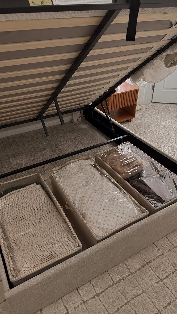 Under-bed storage bins with linens tucked beneath a black metal bed frame.