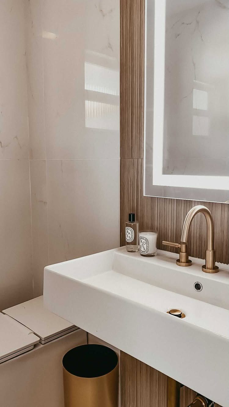 White rectangular sink with gold faucet and gold trash can in modern bathroom