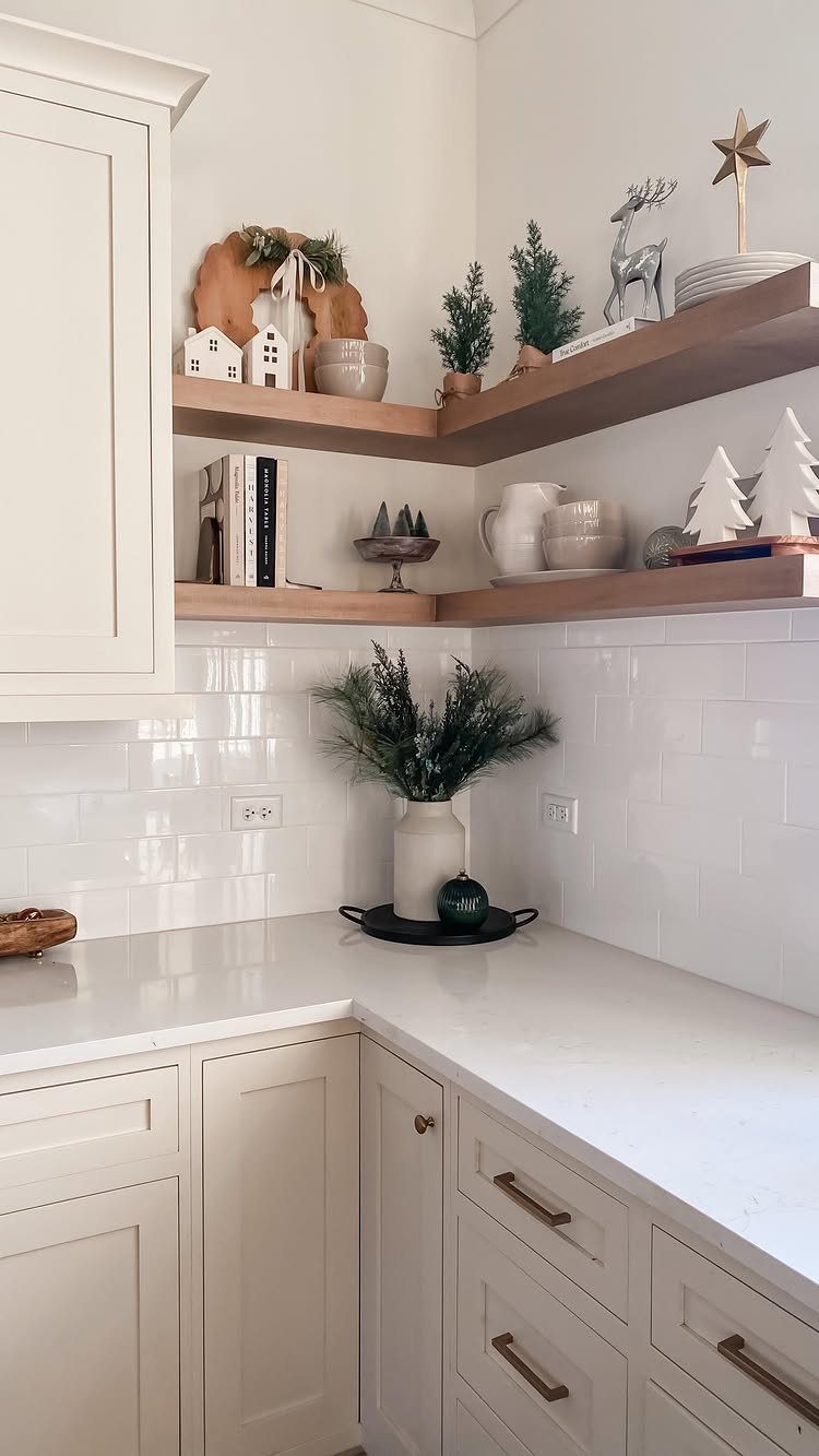 White kitchen corner with wooden floating corner shelves holding decorative home accents.