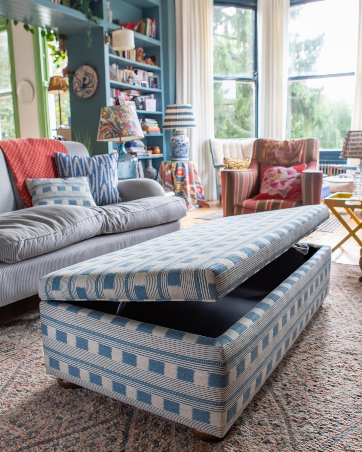 Blue and white patterned ottoman bench with open storage lid in a living room