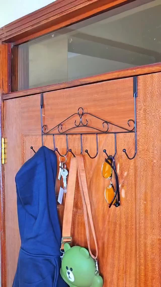 Black metal over-the-door hook rack holding a jacket, keys, bag, and sunglasses.