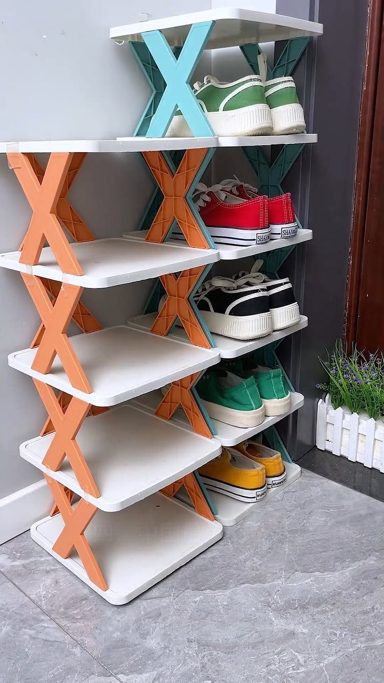 Multi-tiered shoe rack with colorful X-shaped supports holding various sneakers against a wall.