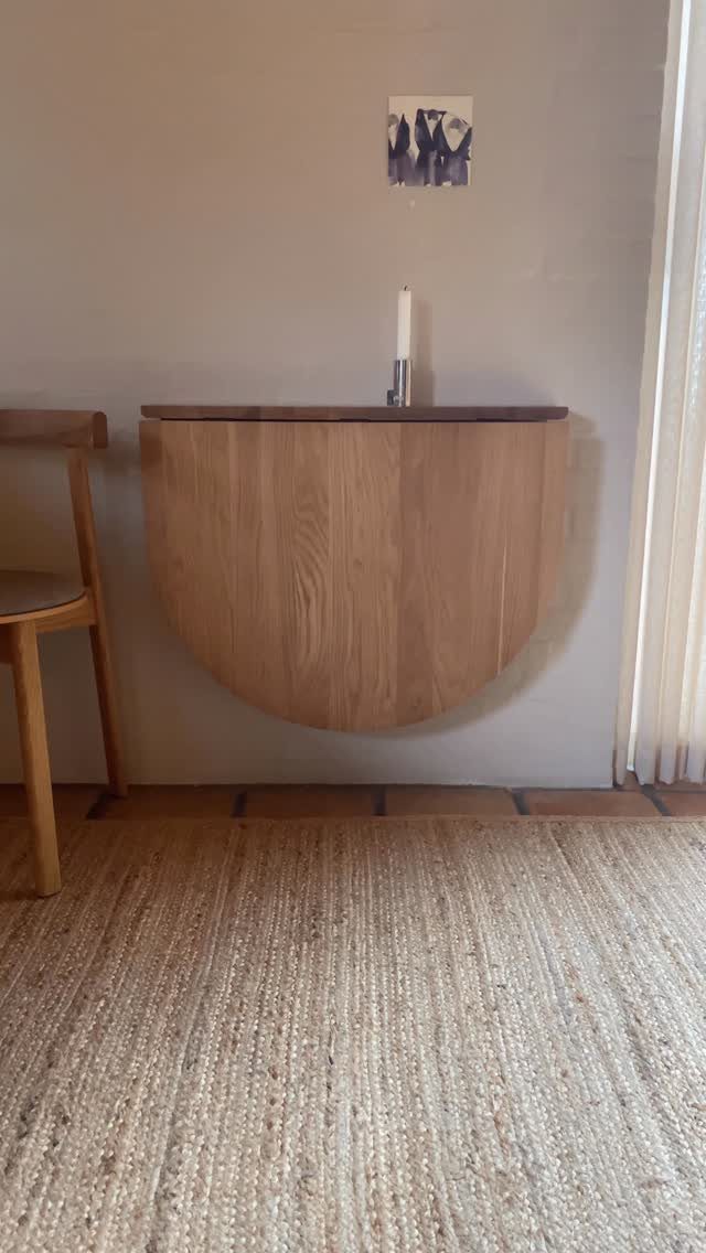 Semi-circular wooden floating console table mounted on a wall above a jute rug.