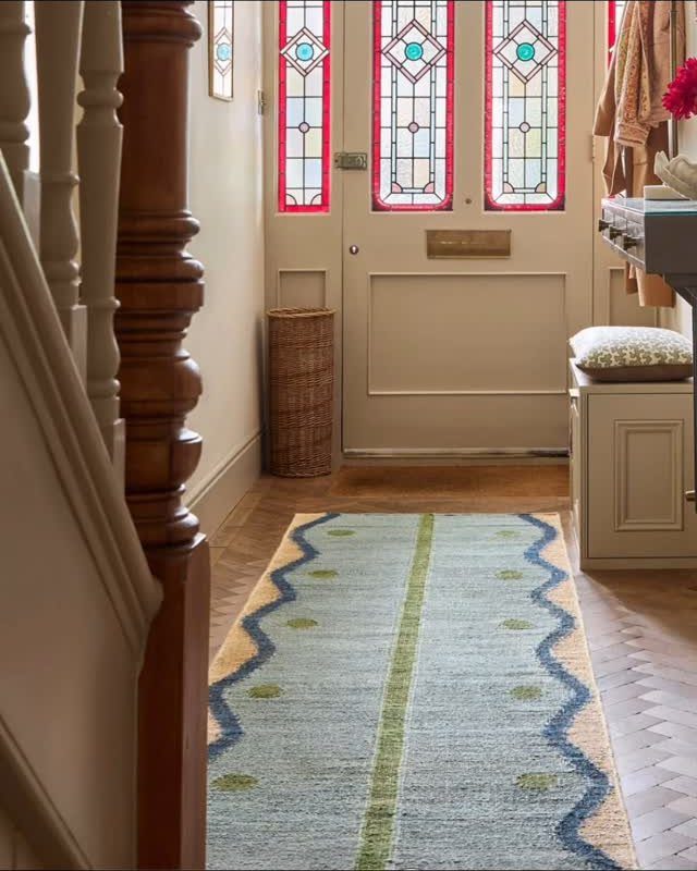 Light blue patterned runner rug in a narrow entryway with a stained glass door.