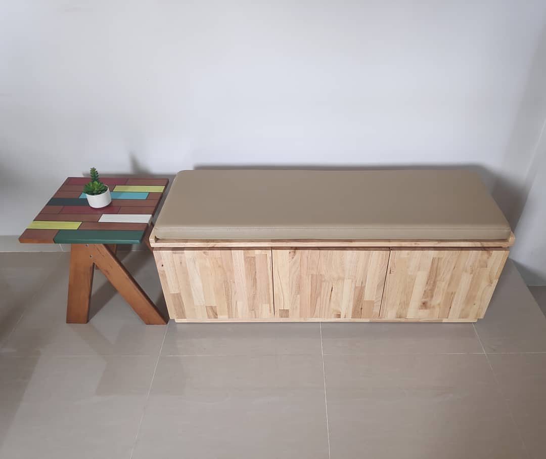 Wooden storage bench with beige cushion and a colorful small side table.