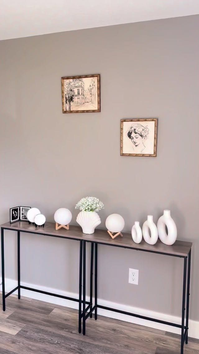 Narrow wooden console table with black metal legs and white decorative vases.