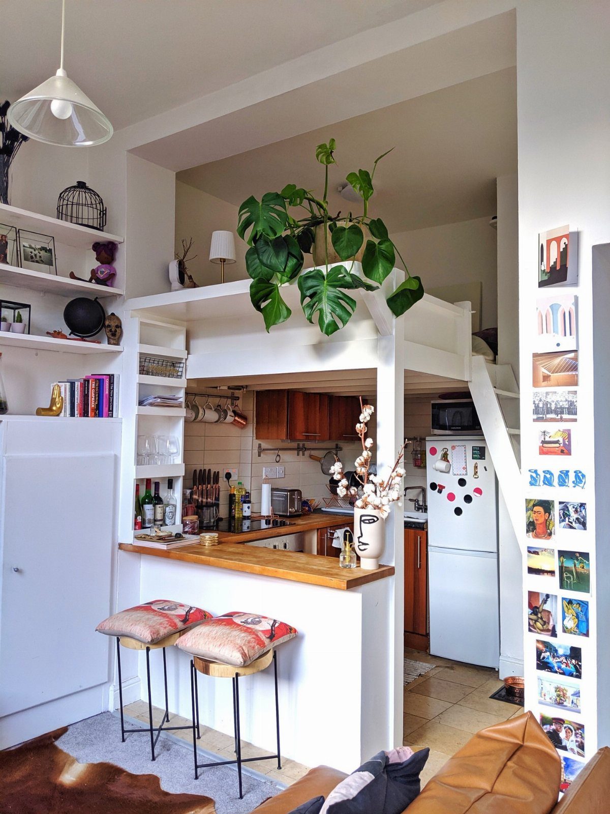 Loft bed positioned over a small kitchen to create separate living zones.