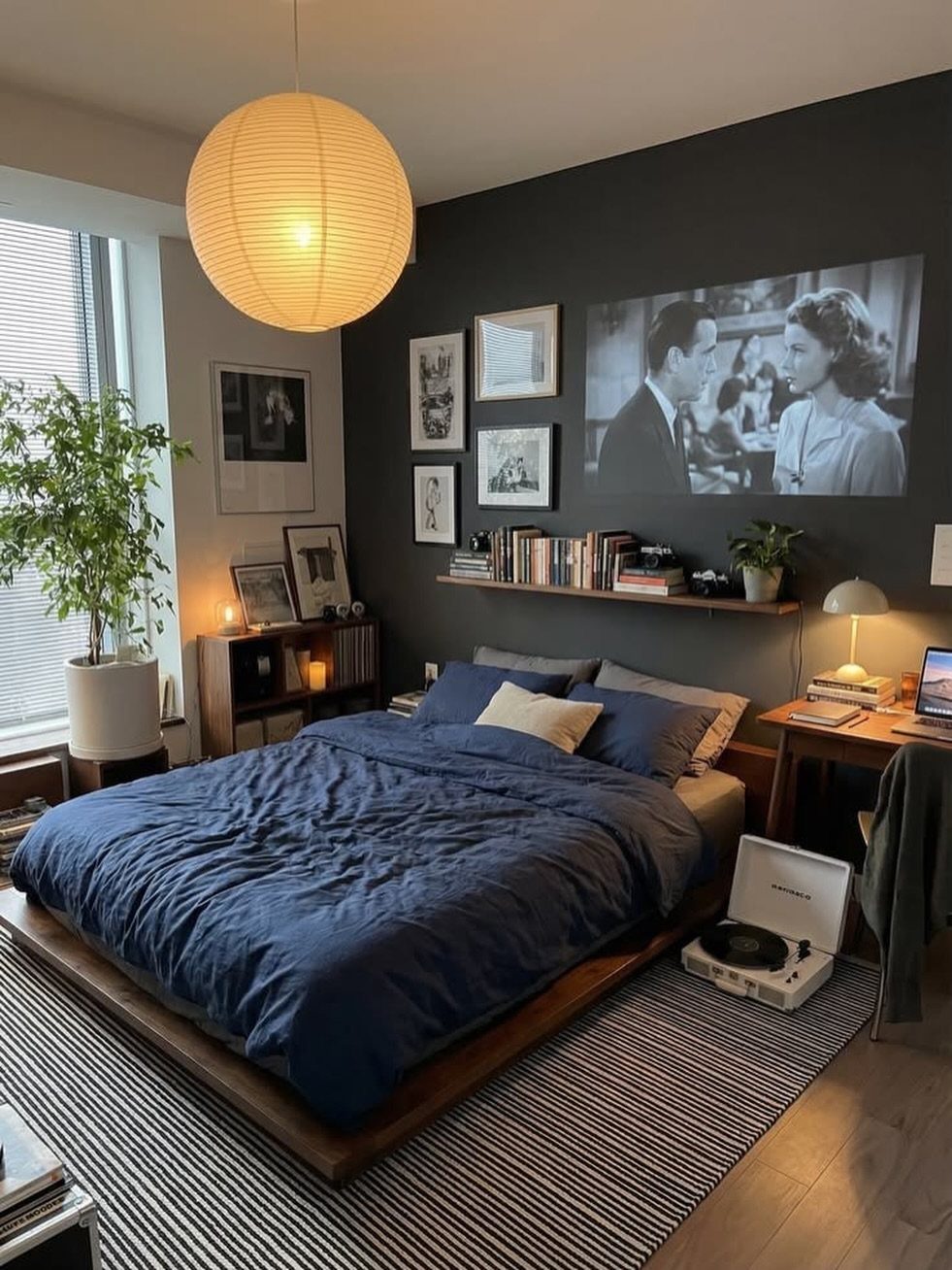 Low wooden platform bed with blue bedding in a cozy studio apartment bedroom