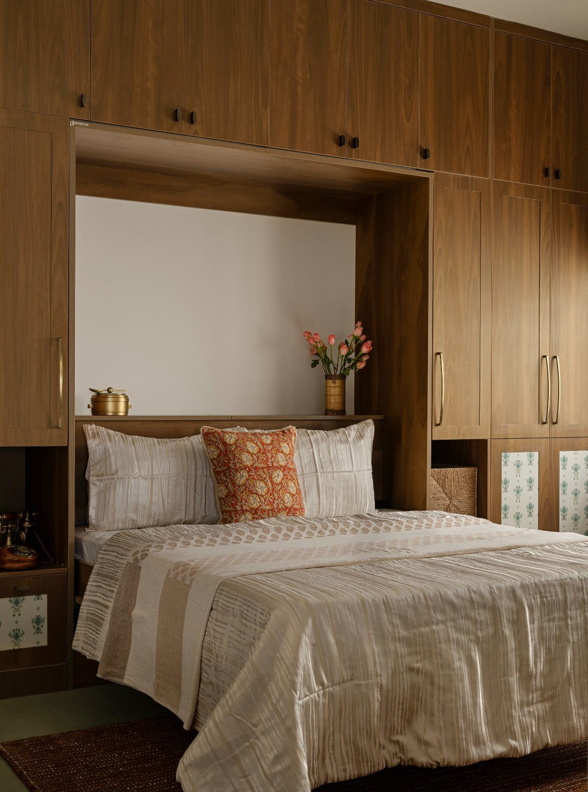 Bed tucked into a wooden wall unit with built-in storage and cabinets.