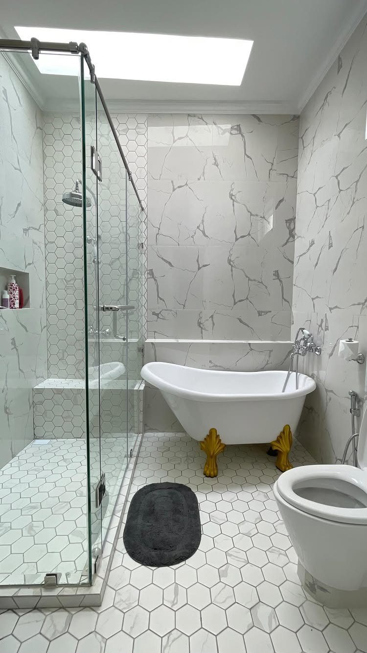 Bright bathroom with a skylight, glass shower, and white clawfoot tub.