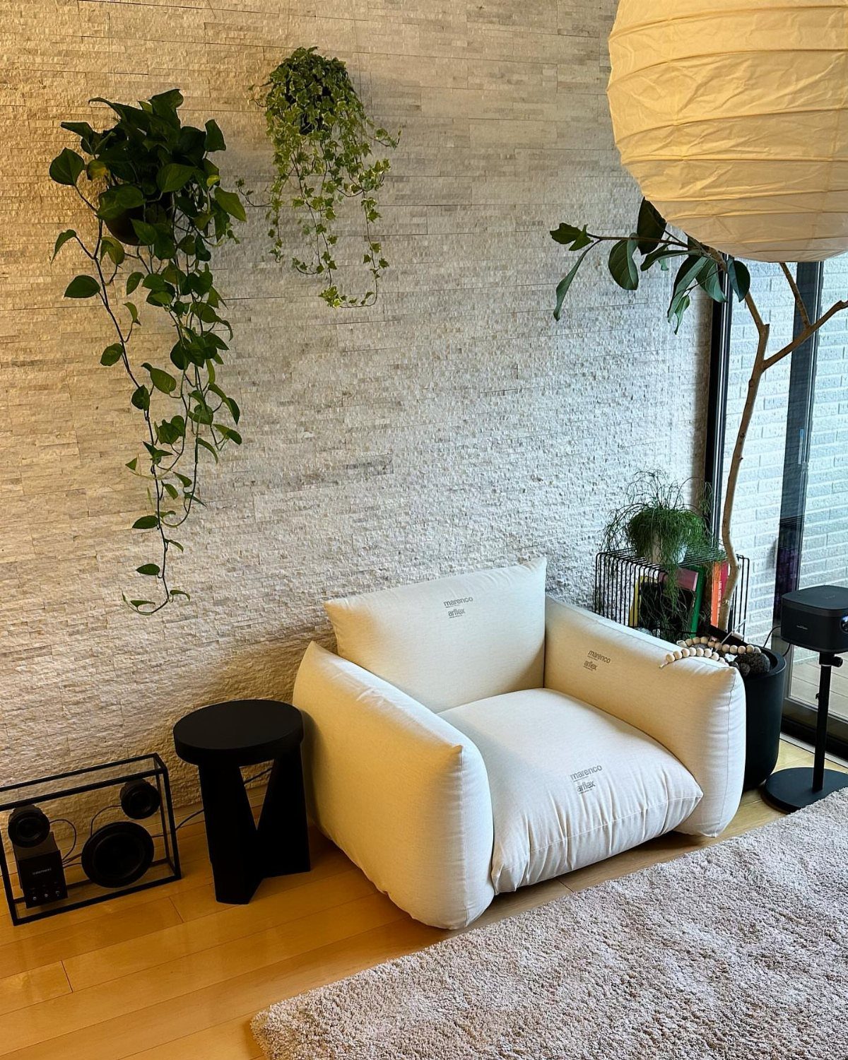 White low-profile modular sofa chair in a room with stone walls and plants.