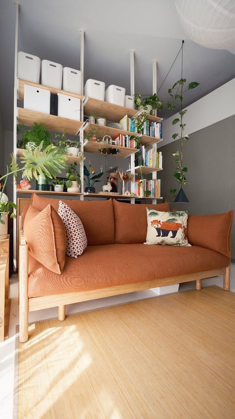 Orange fabric sofa with wooden legs in a bright room with wall shelving.
