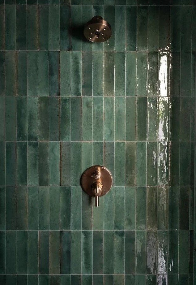 Glossy green vertical tiles with bronze shower fixtures in a modern bathroom.