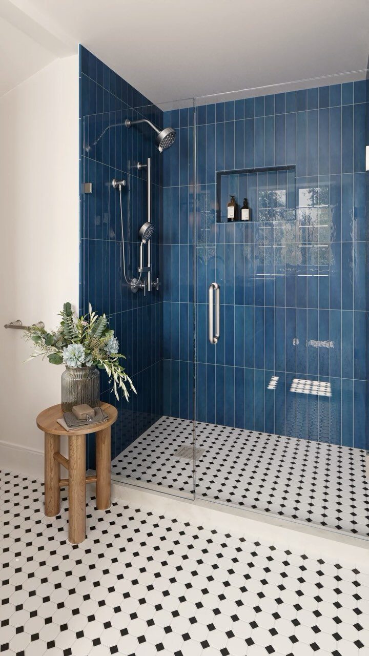 Blue tiled walk-in shower with black and white mosaic floor tiles and glass door
