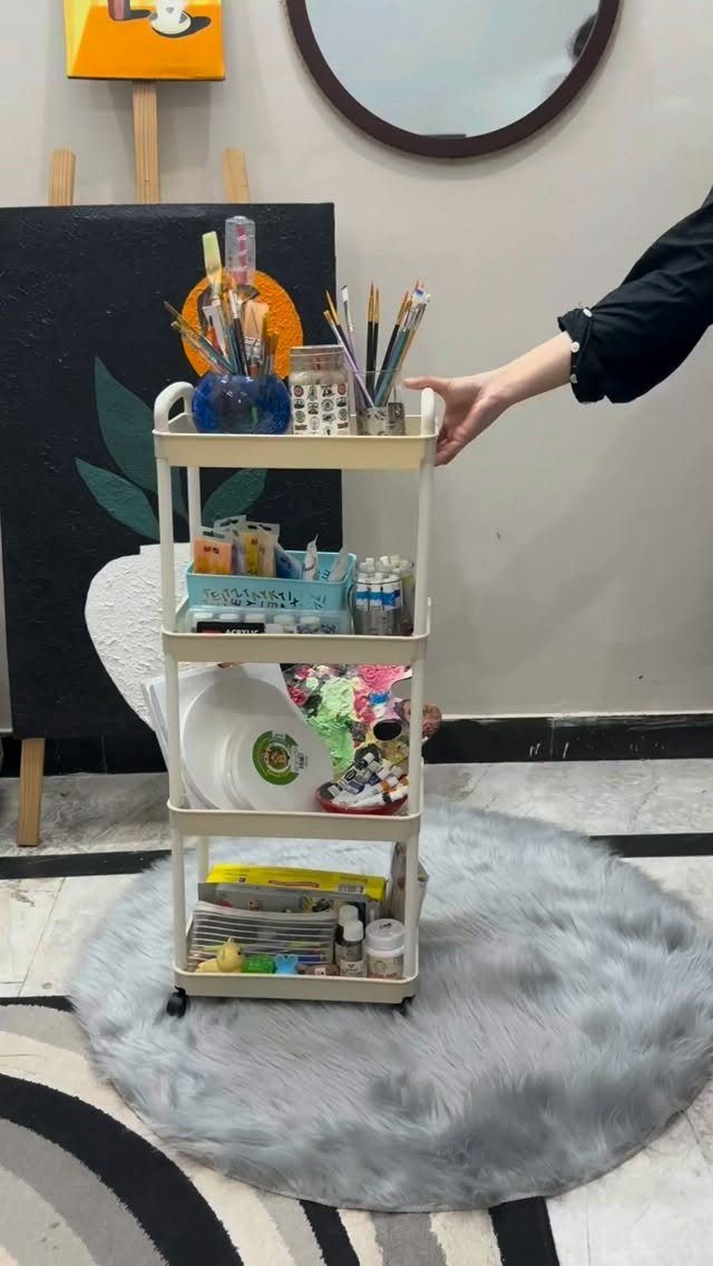 White rolling utility cart filled with art supplies on a grey faux-fur rug