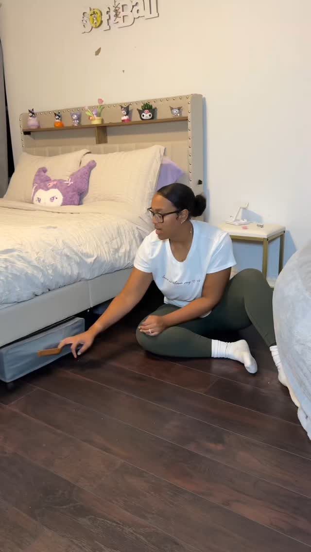 Woman pulling open a storage drawer located underneath a white bed frame.
