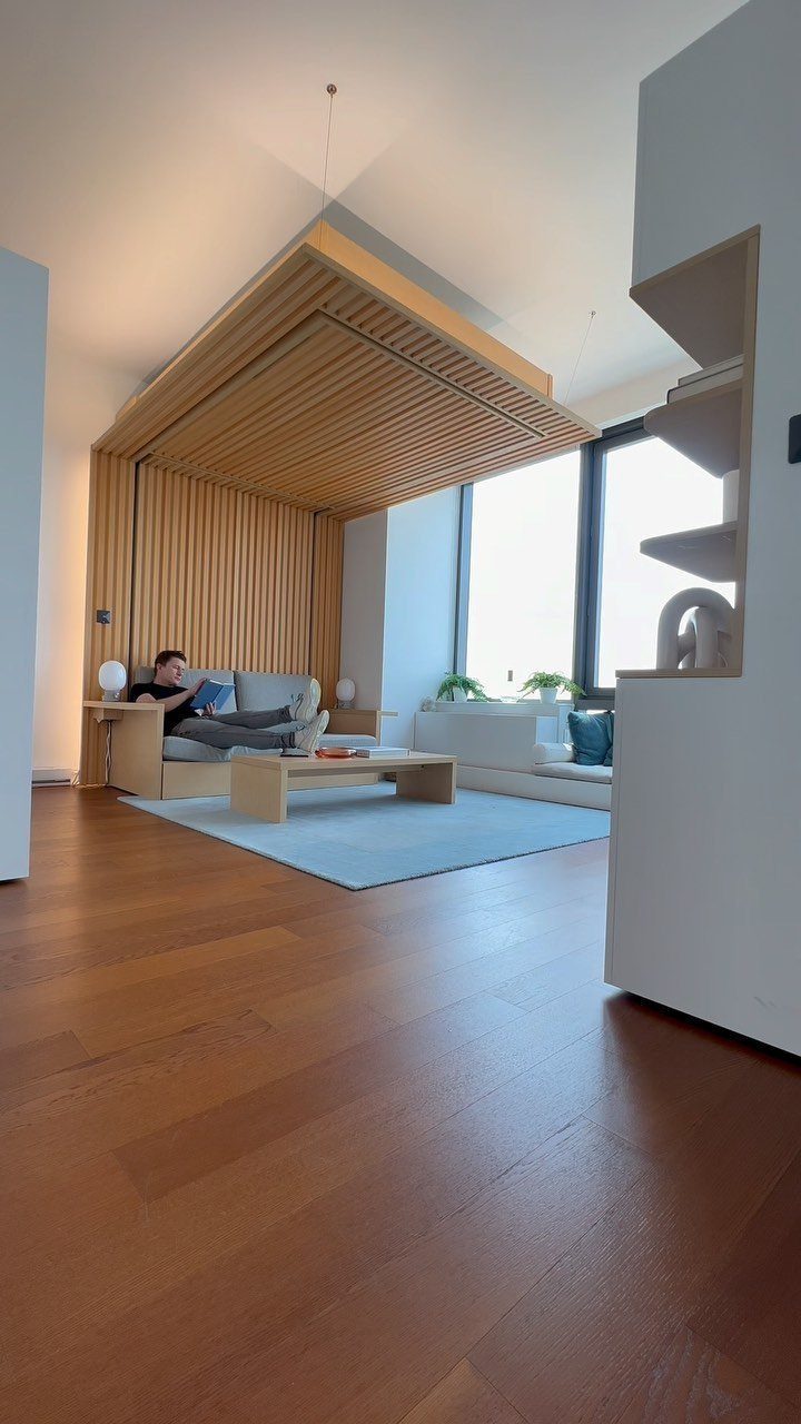 Modern studio apartment with a wooden slatted ceiling feature and light blue rug.