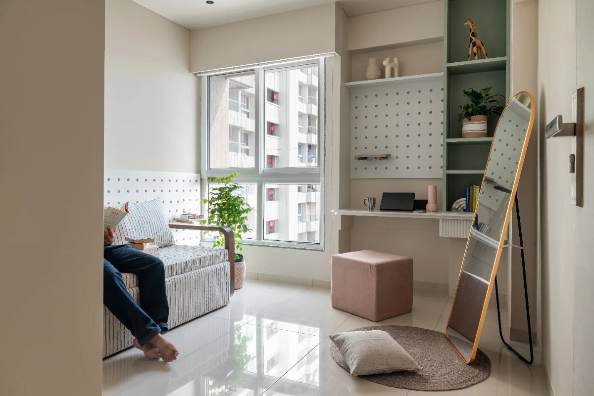 White wall-mounted floating desk in a bright studio apartment with a pink ottoman.