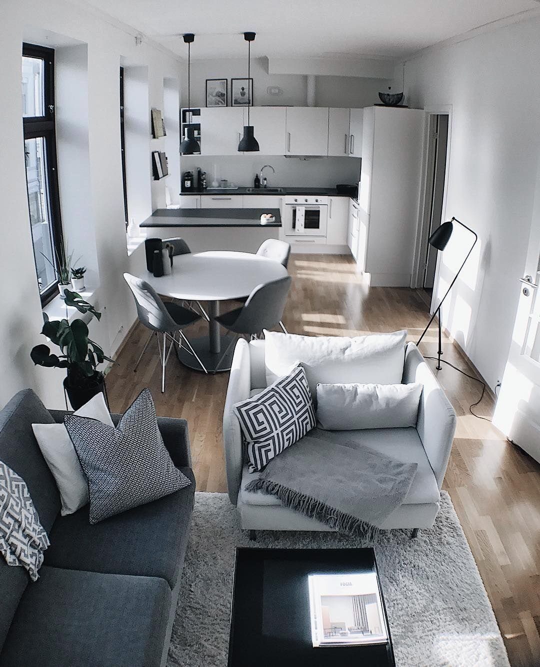 Grey sofa and white armchair arranged on a light grey rug in studio.