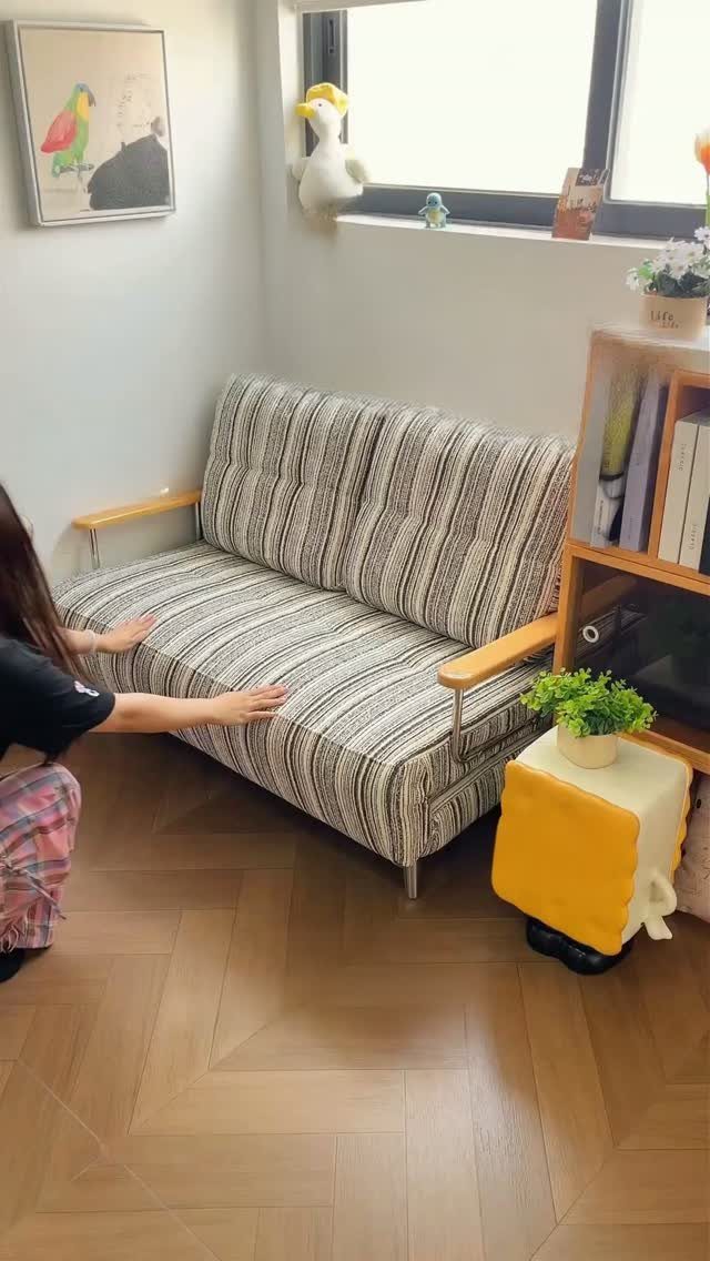 Striped grey and white small sofa in a bright room with wooden floors.