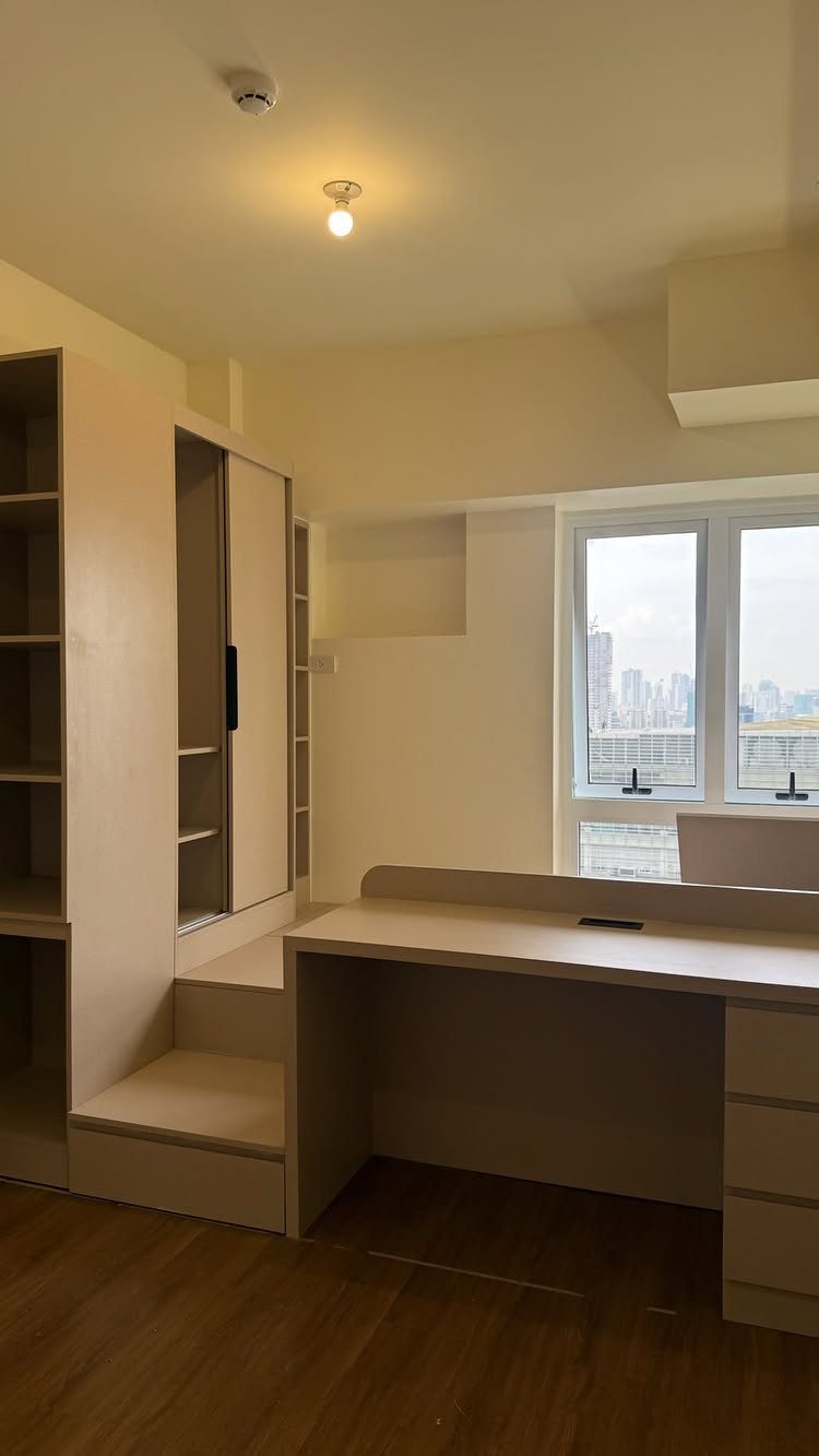 Built-in light beige storage unit with integrated desk and raised platform stairs.