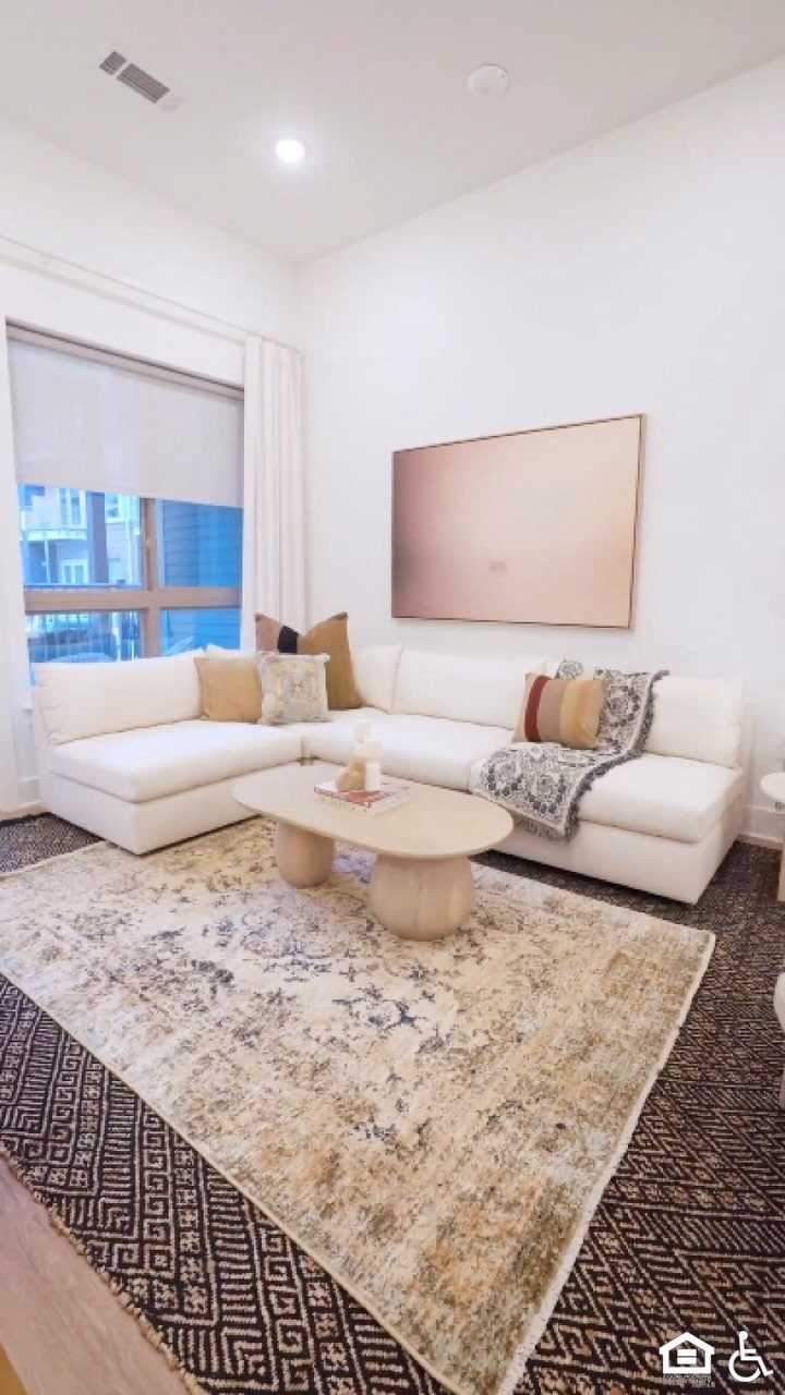 White sectional sofa with pillows and a throw on a patterned area rug.